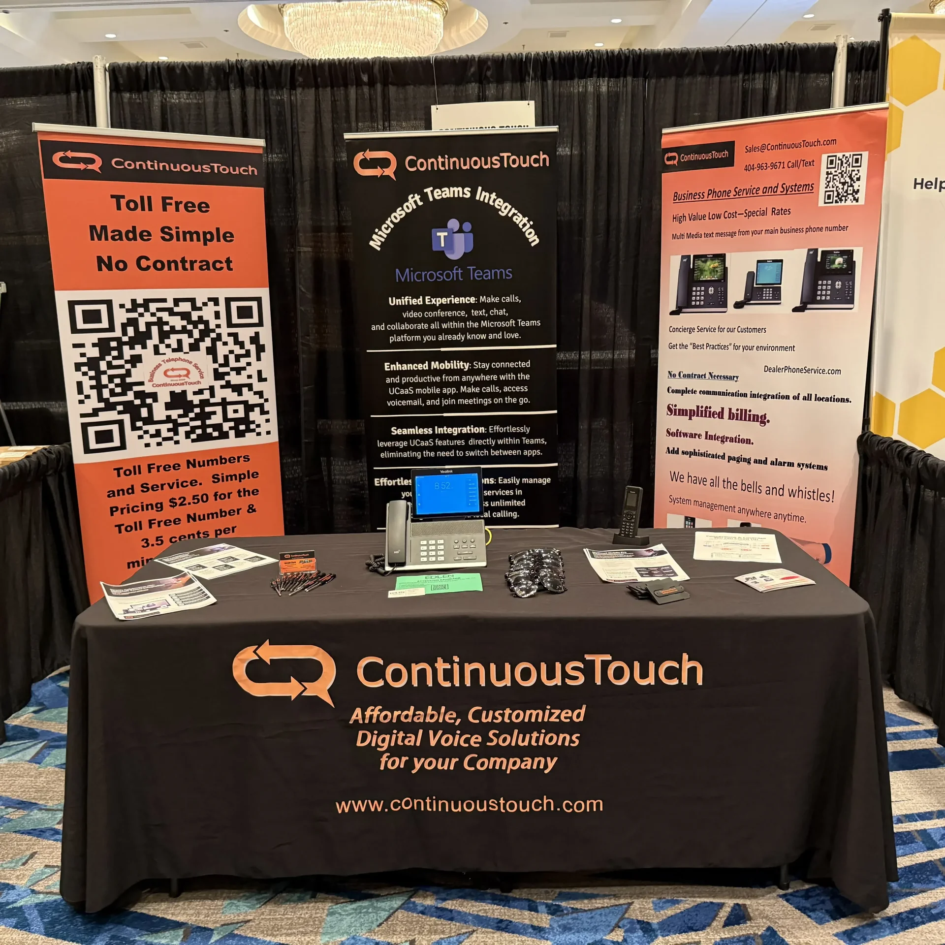 Continuous Touch display booth with business phone service banners, desk phones and information about Microsoft Teams integration.